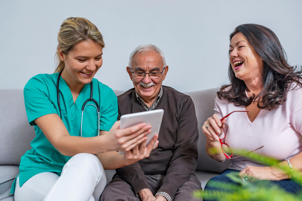 Woman in scrubs talking to older couple