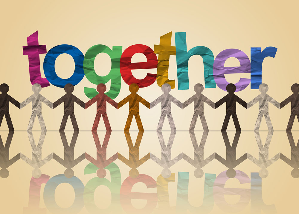 Paper cutout of people of all colors holding hands with a multi color sign that says "together"