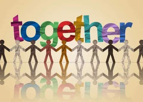 Paper cutout of people of all colors holding hands with a multi color sign that says "together"